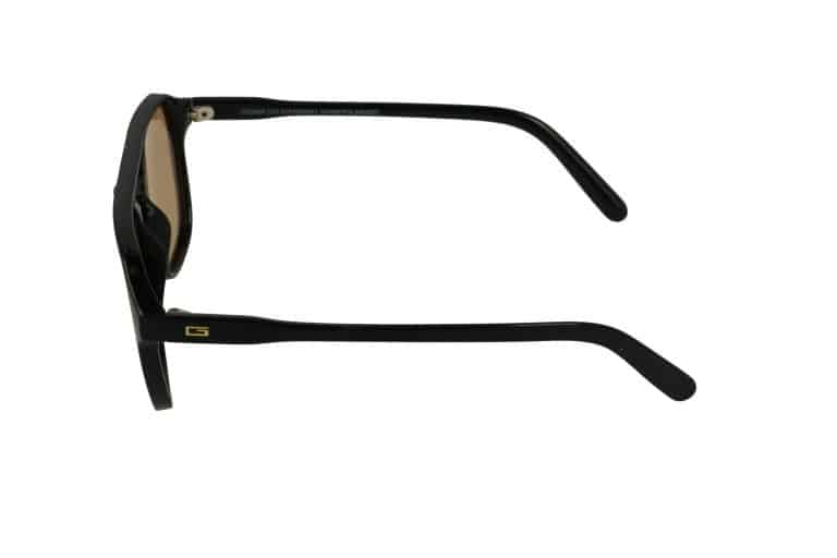 מבט צדדי על משקפי שמש שחורים עם עדשות חומות ולוגו G קטן מזהב על הזרוע, מבודדים על רקע לבן.